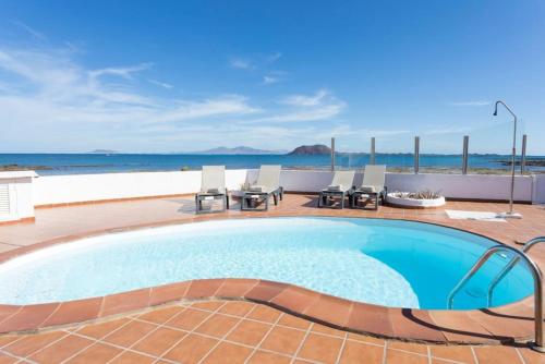 a swimming pool with a view of the ocean at Corralejo Beachfront Villa Remos with Lobos Island View, Private Pool, Wifi & BBQ by Amazzzing Travel in Corralejo