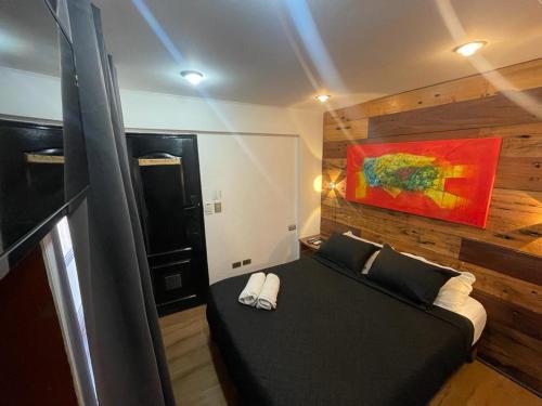 a bedroom with a black bed and a painting on the wall at Tremo Parque Bustamante in Santiago