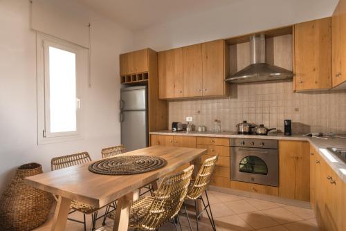 a kitchen with a wooden table and some chairs at Villa Delmar - Delmar Collection in Pollonia
