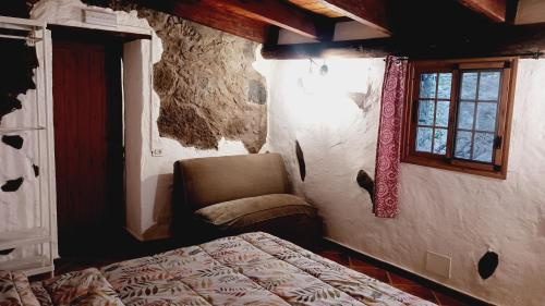 a bedroom with a bed and a chair and a window at Casita el Parral in Tejeda