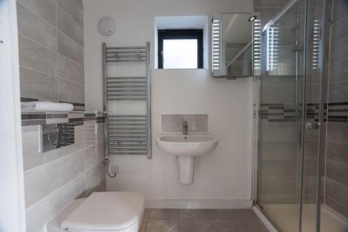 a white bathroom with a toilet and a sink at Attractive pet friendly beach house in Westward Ho in Westward Ho