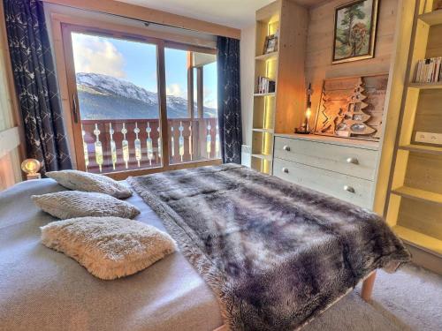 a bedroom with a bed with a large window at Charmant 2 pièces cabine skis aux pieds, parking inclus - FR-1-182-245 in Les Allues