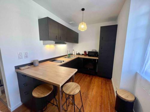 une cuisine avec une table en bois et deux tabourets dans l'établissement Appartement Climatisé 4 personnes / Centre-ville, à Besançon