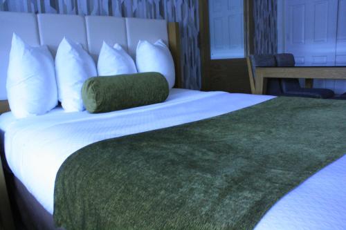 a bed with white pillows and a green pillow at Split Rock Resort in Lake Harmony
