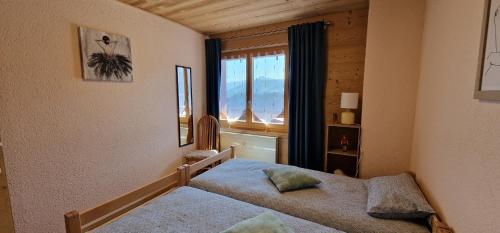 a bedroom with two beds and a window at Bleuet K5 in Champoussin