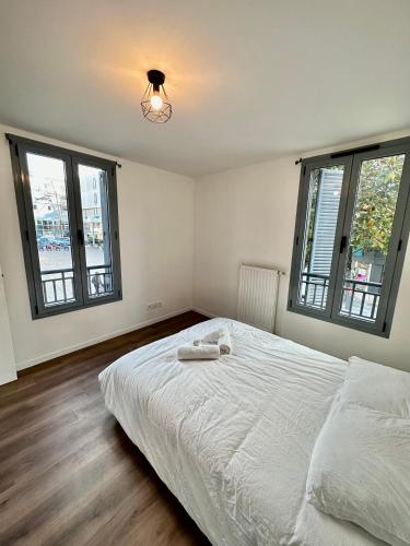 a bedroom with a white bed and two windows at Magnifique apartment in Paris / Bagnolet 101 in Bagnolet