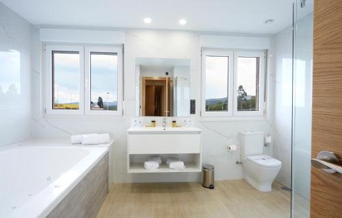 a white bathroom with a tub and a sink and a toilet at Hotel Arias Aeropuerto in Santiago del Monte