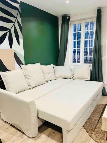 - un canapé blanc dans une pièce dotée d'un mur vert dans l'établissement Les Orchidées, à Rouen