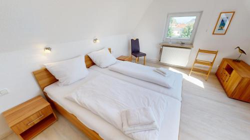 ein Schlafzimmer mit einem großen Bett mit weißer Bettwäsche in der Unterkunft GAST-ZEIT Kliff 3 in Grömitz