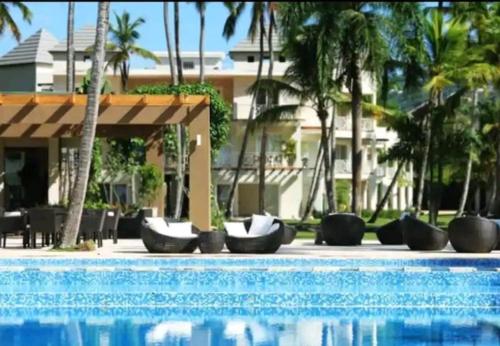 una piscina en un complejo con sillas y palmeras en Apartamento Coson Bay Las Terrenas, en Las Terrenas