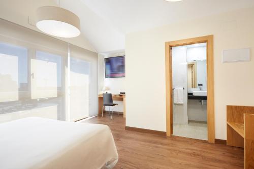 a bedroom with a bed and a desk and a mirror at Hotel Arias Aeropuerto in Santiago del Monte
