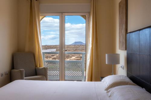 a bedroom with a bed and a window with a view at Villas y Apartamentos El Sultan in Corralejo