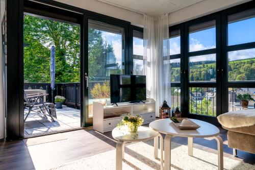 uma sala de estar com televisão e janelas grandes em Sunside Winterberg em Winterberg
