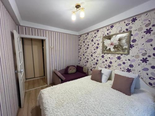 a bedroom with a white bed and a purple chair at 2-на квартира вул. Михайла Донця 5, поруч НАУ, КПІ, клініка Шалімова, метро Шулявська -15 хв in Kyiv