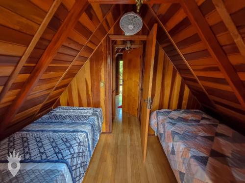 two beds in a room with a attic at Chalé a beira de lago com churrasqueira em SP in Indaiatuba