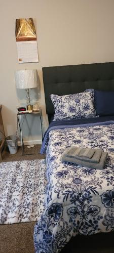 ein Schlafzimmer mit einem blauen und weißen Bett und einer Lampe in der Unterkunft Central Pointe Pad in Riverdale