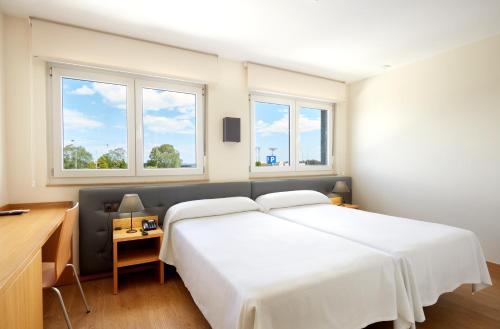 Monte的住宿－Hotel Arias Aeropuerto，卧室设有一张白色大床和两个窗户。