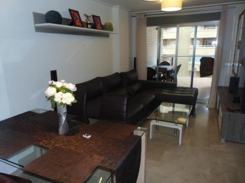 a living room with a couch and a table with flowers at Apartamentos varios con 2 dorm en Marina Dor , la playa de Amplaries 47 , vista lateral al mar in Oropesa del Mar