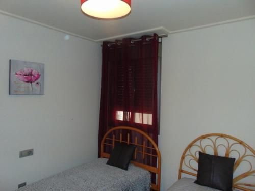 a bedroom with two beds and a window with red curtains at Apartamentos varios con 2 dorm en Marina Dor , la playa de Amplaries 47 , vista lateral al mar in Oropesa del Mar