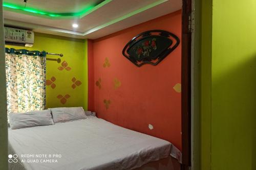 una camera con un letto e una parete verde e arancione di OYO Nirmal Guest House a Guwahati