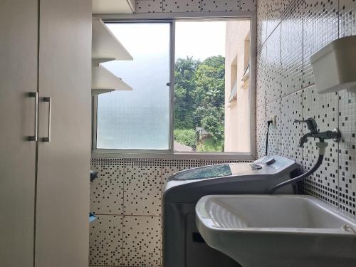 a bathroom with a sink and a window at Apto em frente à praia em Caraguatatuba in Caraguatatuba