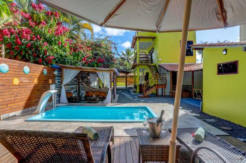 uma piscina com um guarda-sol, uma mesa e cadeiras em Pousada Endlessenses em Itacaré