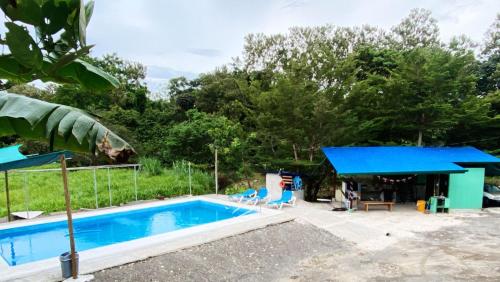 a swimming pool and a house with a blue roof at Residencia las brisas Griegas in Quepos