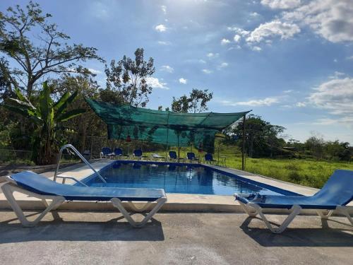 a swimming pool with two lounge chairs next to it at Residencia las brisas Griegas in Quepos