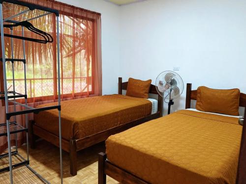 a room with two beds and a fan and a window at Residencia las brisas Griegas in Quepos