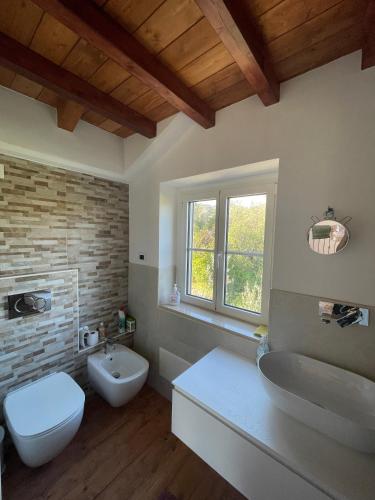 une salle de bain avec deux lavabos et un WC et une fenêtre dans l'établissement La casa dell'ulivo, à Imperia
