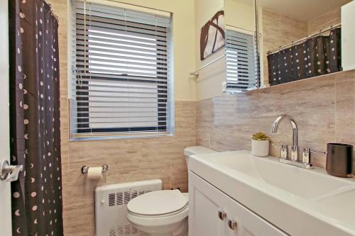 a bathroom with a toilet and a sink and a window at 2BR Roomy & Stylish Apartment in Rogers Park - Sheridan N2 in Chicago