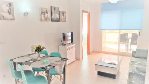 een woonkamer met een tafel en stoelen en een televisie bij Apartamentos varios con 2 dorm en Marina Dor , la playa de Amplaries 1-47 , vista lateral al mar in Oropesa del Mar