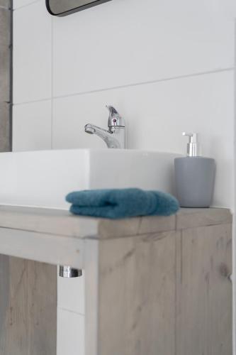 a bathroom sink with a blue towel on a counter at Wildzicht Cosy Cabins in 't Zand