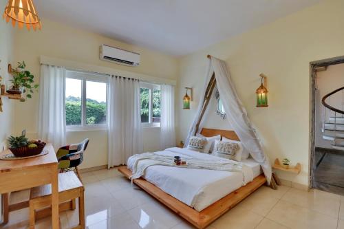 1 dormitorio con 1 cama, escritorio y ventanas en Alaya Stays Luxurious 4BHK Farm with Pvt Pool in Manesar, en Gurgaon