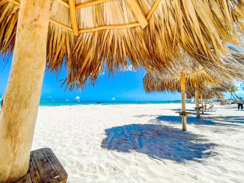 a straw umbrella on a sandy beach with the ocean at OCEANFRONT & Garden View VILLAS Hotel WIFI BBQ Parking Los Corales beach CLUB & SPA in Punta Cana