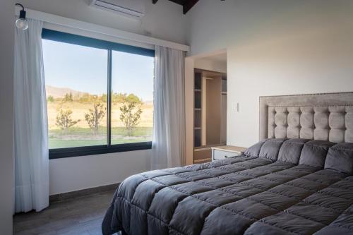 ein Schlafzimmer mit einem Bett und einem großen Fenster in der Unterkunft Los Alerces Resort, Hotel & Spa in San Andres de las Sierras