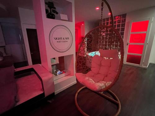 une chambre avec une chaise dans une chambre avec des lumières roses dans l'établissement Metz Détente Un Séjour à Part, à Metz