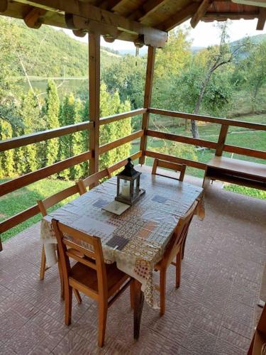 a table and chairs on a porch with a view at "Kod dva kestena"Warm and cozy house with lake view sauna in Međuvršje