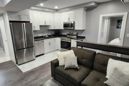 a kitchen with white cabinets and a couch in a room at 12- Exec 1BD-Wifi-AC-Workspace in Windsor