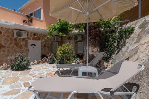 een tafel en stoelen en een parasol op een patio bij Eleni villa in Saktoúria