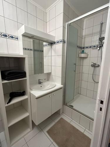 a white bathroom with a shower and a sink at Appartement Brussels Expo Atomium in Grimbergen