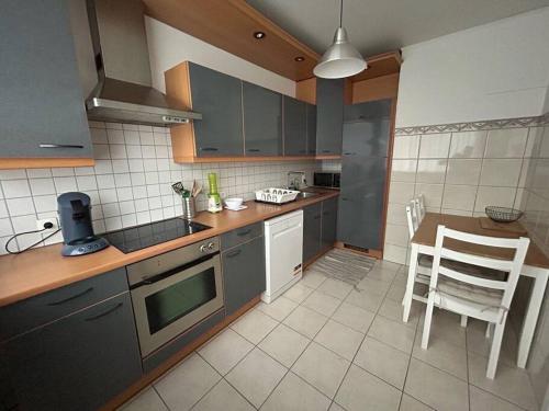 eine Küche mit grauen Schränken sowie einem Tisch und Stühlen in der Unterkunft Appartement Brussels Expo Atomium in Grimbergen