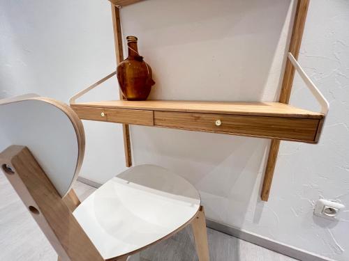 ein Holzregal mit einer Vase und einem Stuhl in der Unterkunft Le Briotin Moderne Plein Pied Un-Séjour-à-Part in Briey