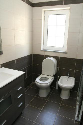 CarapitoにあるCasa da Pizzariaのバスルーム(トイレ、洗面台付)、窓が備わります。
