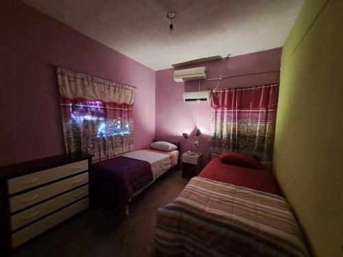 a bedroom with two beds and pink walls at Alojamiento Marlugm in Corrientes