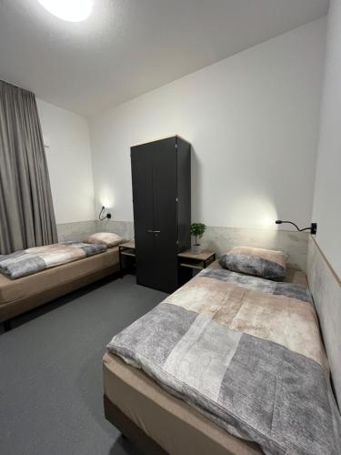 a bedroom with two beds and a cabinet at Longhouse Aparthotel in Dreieich