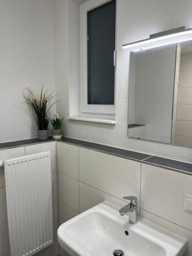 a white bathroom with a sink and a mirror at Longhouse Aparthotel in Dreieich