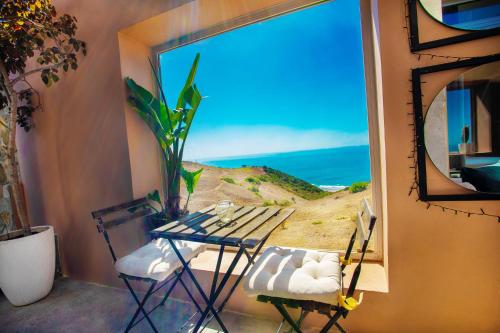 a table and chairs in front of a window with a beach view at Hill Valley Asilah - Luxury Living & Boutique Hotel in Asilah