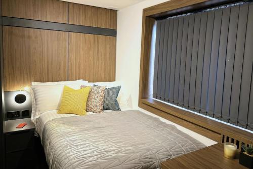 a bedroom with a bed with yellow pillows and a window at Lovely 1 Bed Studio 1B near Royal Infirmary and DMU in Leicester