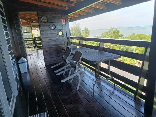 a porch with a table and chairs on a deck at Tehuarupe Surf Studios in Haapiti